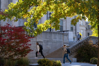 Students climb the steps of the Old Capitol amid fall color. Photo by Justin Torner.
