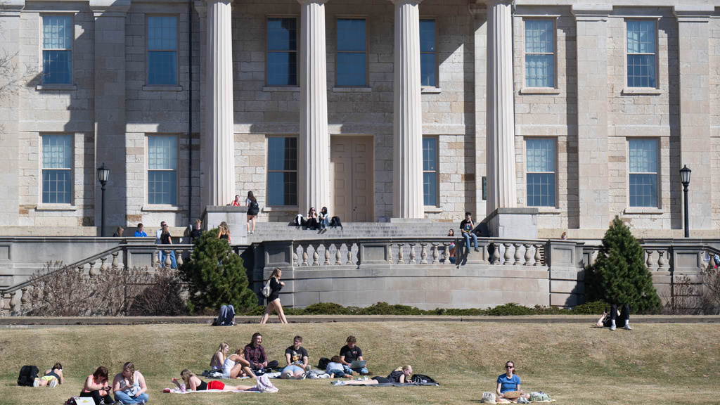 A student studies while listening to music by the pillars of the Old Capitol. Photo illustration by Tim Schoon.